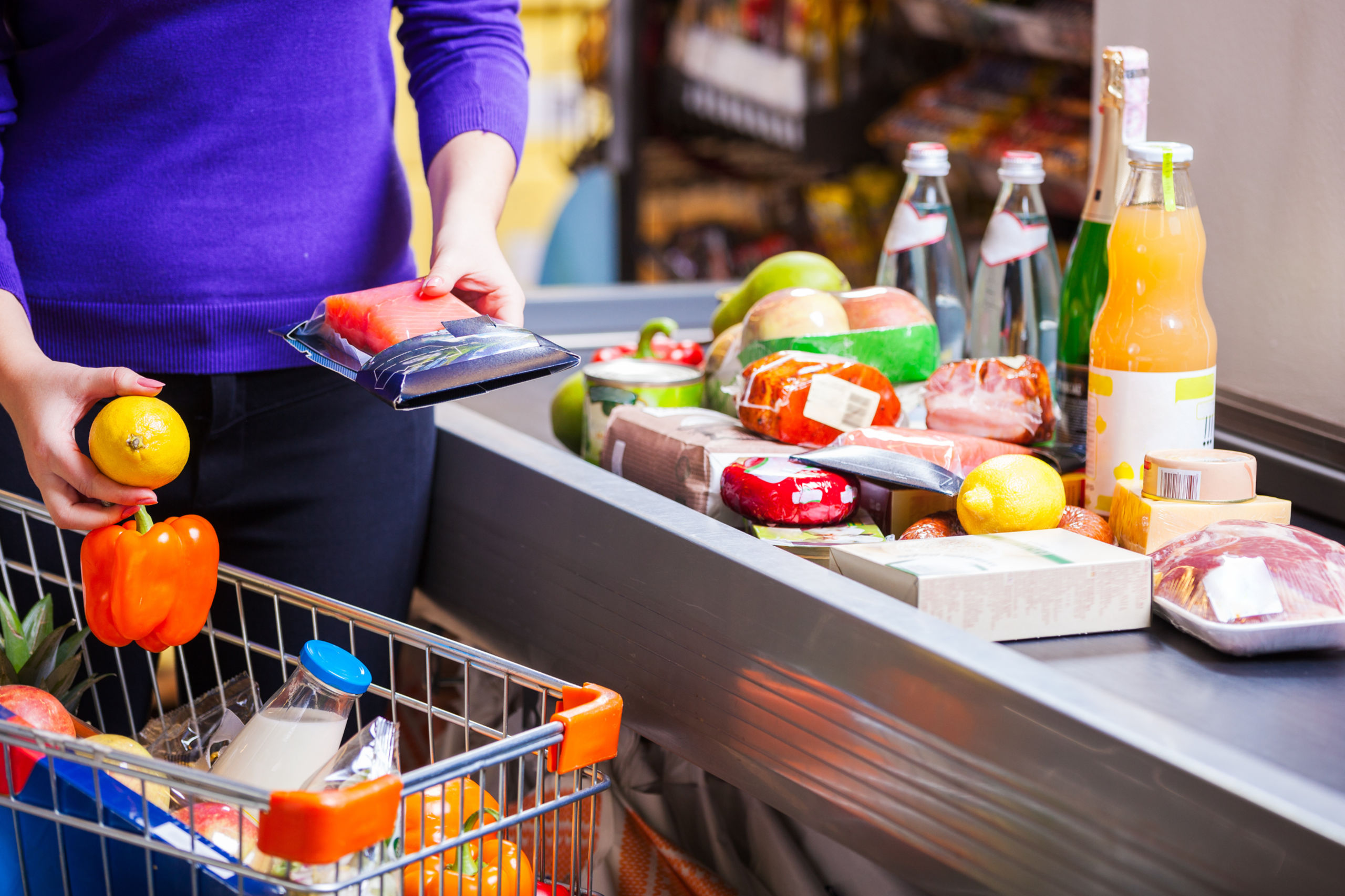 Eine Frau zahlt ander Kasse vom Supermarkt. Die Preissteigerung ist ein Problem.