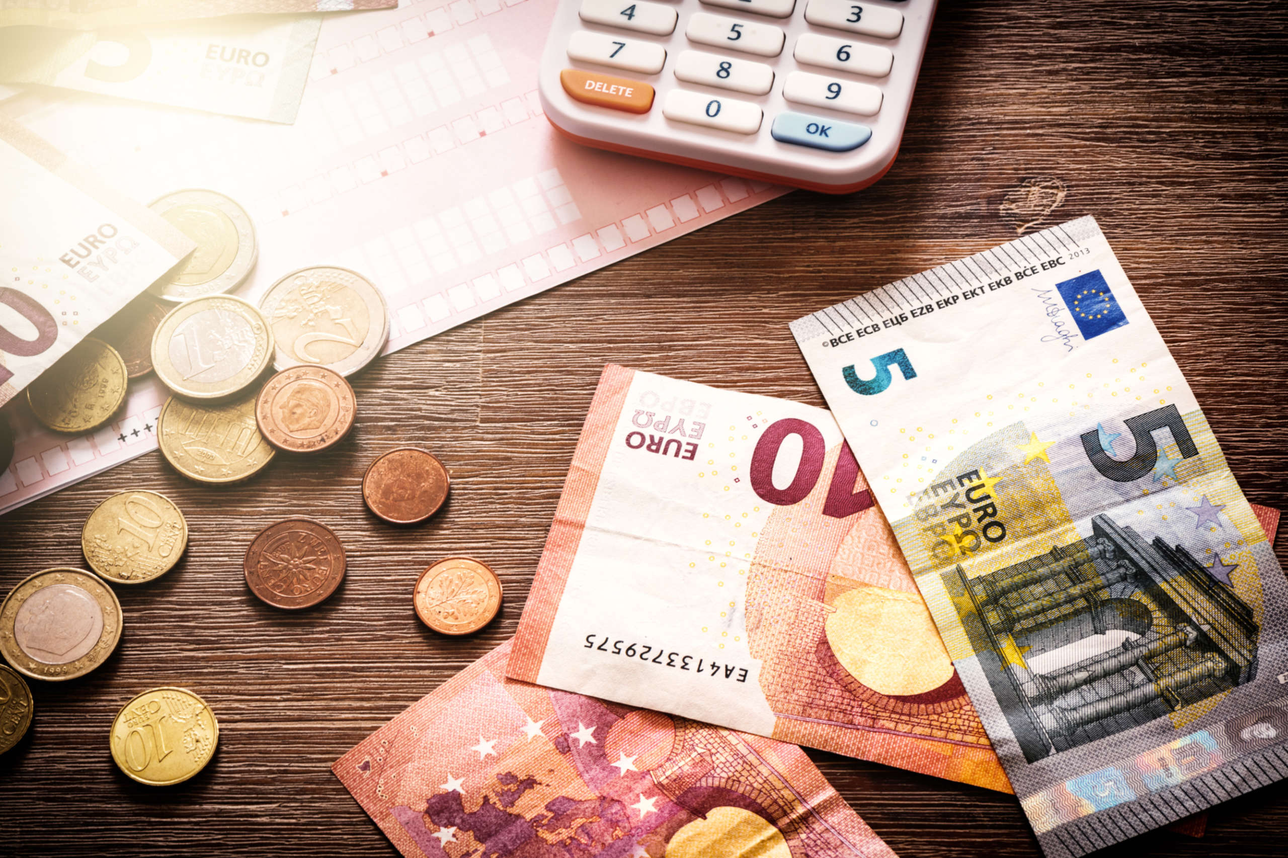 Eine kleinere Summe Geld liegt neben einem Taschenrechner auf dem Tisch. Wer Arbeitslosengeld in Österreich bekommt, muss seine Ausgaben exakt kalkulieren.