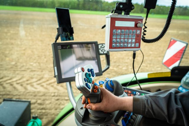 Ein Landwirt bestellt in einem moderene Traktor mit vielen Displays ein Feld. die Digitalisierung verändert auch die Landwirtschaft.