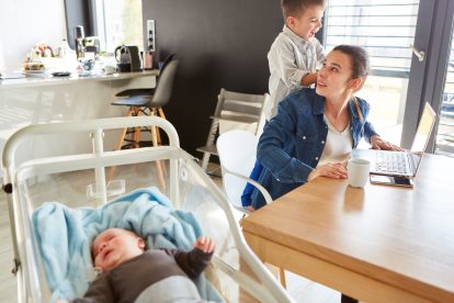 Eine gestresste Mutter kümmert sich um ihre Kinder und arbeitet nebenbei in Teilzeit.