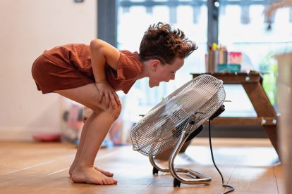 Ein Kind spielt mit einem Ventilator. Symbolbild für Hitze am Arbeitsplatz, die Kinder und Pädagog:innen trifft.