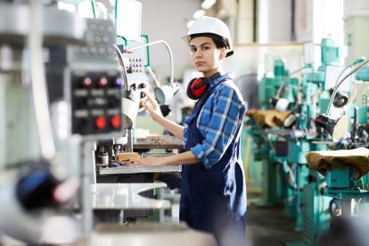 Eine Frau steht vor einer Maschine, die Armbänder für ihren herstellt. Symbolbild für die Industriepolitik.