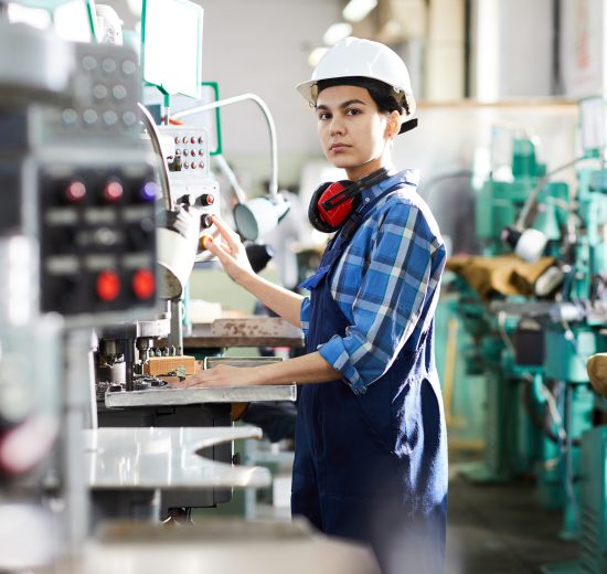 Eine Frau steht vor einer Maschine, die Armbänder für ihren herstellt. Symbolbild für die Industriepolitik.