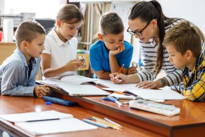 Eine Lehrerin erledigt mit Schüler:innen eine Übung. Symbolbild für Ganztagsschulen.