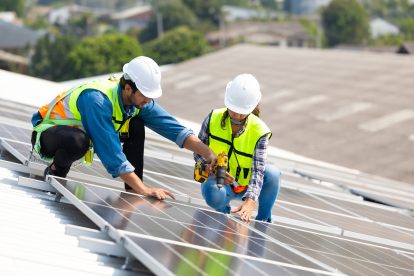 Arbeiter installieren eine solaranlage auf eienm Dach. Clara Paillard spricht im Interview über Umweltschutz und Arbeitsplätze.