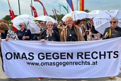 Die Omas gegen Rechts mit Susanne Scholl hinter einem Transparent auf einer Demo.