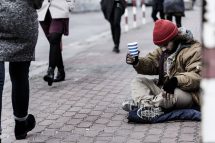 Ein obdachloser Mensch bettelt in der Straße um Geld.