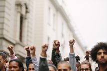 Menschen in einem Protest, strecken ihre Hände hoch, um sich für Demokratie einzusetzen.