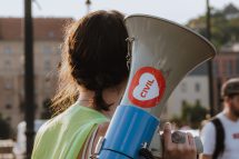 Eine Frau hält auf einer Demonstration ein Megafon in der Hand. Symbolbild für Arbeitsrechte in Ungarn.